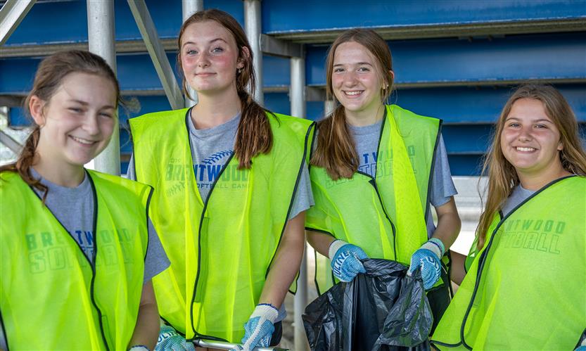 Four girls smile while wearing neon vests